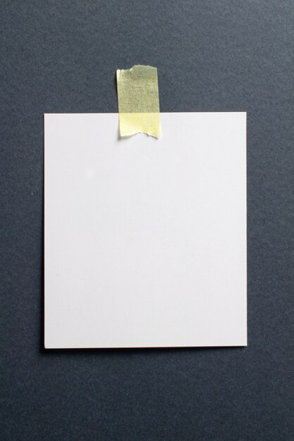 Blank photo frame with soft shadows and yellow scotch tape on black craft paper background 