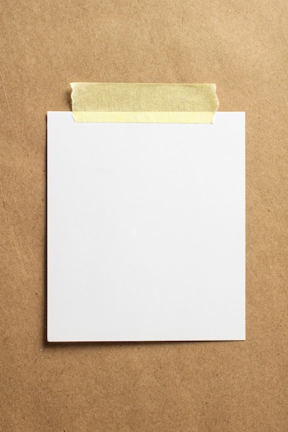 Пустая рамка для фотографий с мягкими тенями и желтой скотчем на фоне крафт-бумаги
