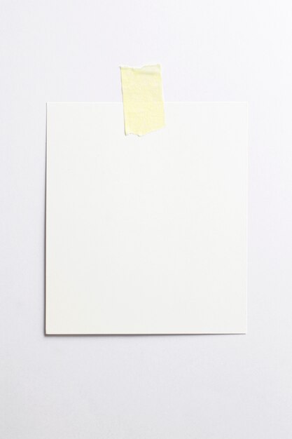 Blank photo frame with soft shadows and yellow scotch tape isolated on white paper background 