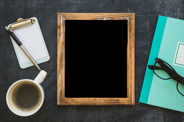 Blank picture frame; coffee cup and stationeries on blackboard
