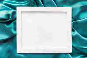 Free photo blank picture frame on turquoise satin fabric