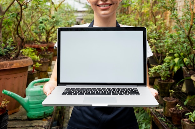 Free photo blank screen laptop in a greenhouse