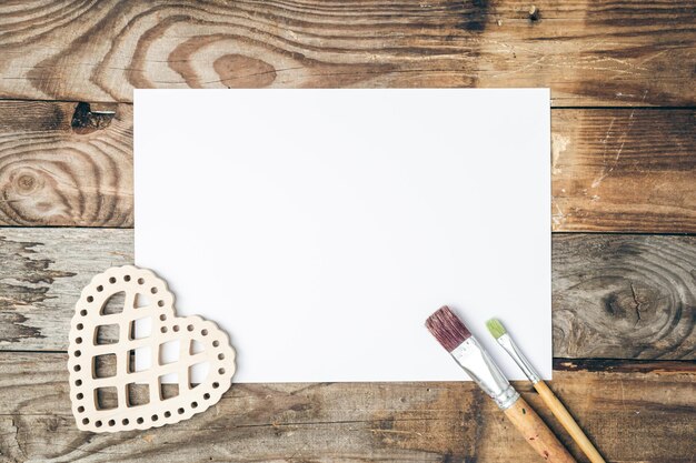 Blank sheet of paper and brushes for drawing on a wooden background flat lay