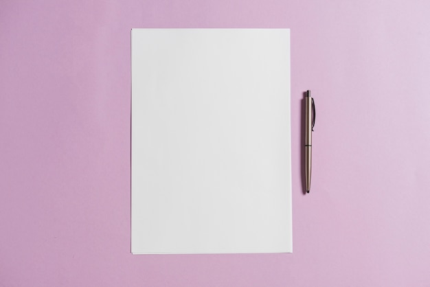 Пустой лист бумаги и ручка на розовом фоне