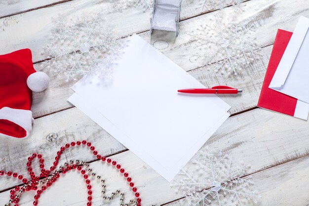 blank sheet of paper on the wooden table with a pen and  Christmas decorations.