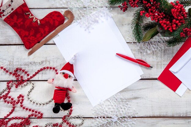 blank sheet of paper on the wooden table with a pen and  Christmas decorations.