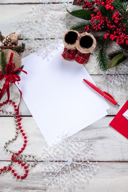 чистый лист бумаги на деревянном столе с ручкой и рождественскими украшениями.