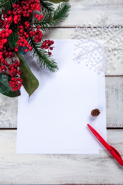 blank sheet of paper on the wooden table with a pen and  Christmas decorations.