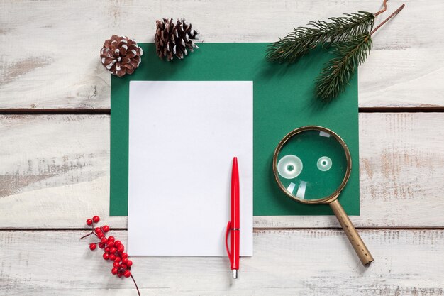 blank sheet of paper on the wooden table with a pen and Christmas decorations.