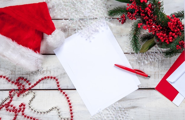 The blank sheet of paper on the wooden table with a pen and Christmas decorations.