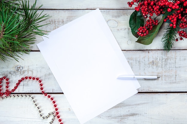 blank sheet of paper on wooden table with a pen and Christmas decorations