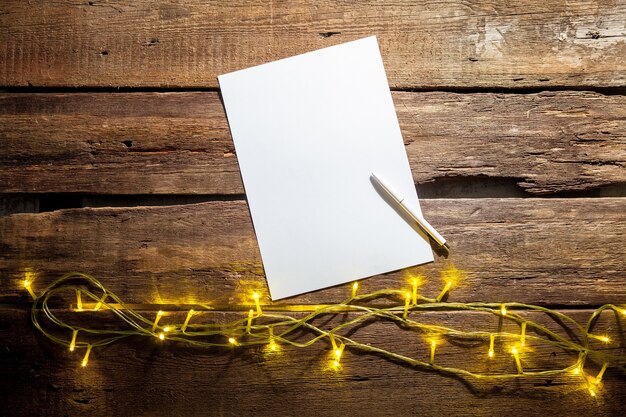 blank sheet of paper on wooden table with a pen and Christmas decorations