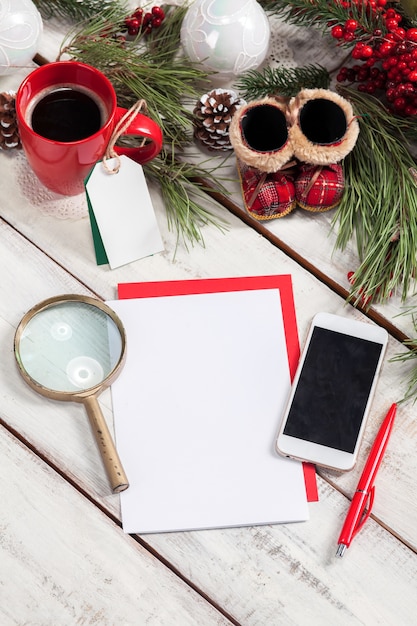 blank sheet of paper on the wooden table with a pen,  phone and Christmas decorations.