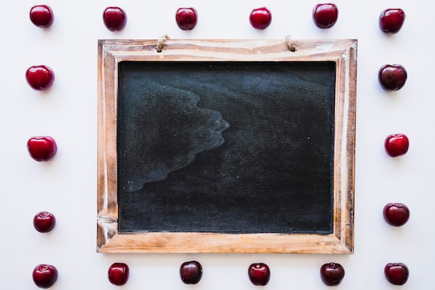 Free photo blank slate surrounded by cherries