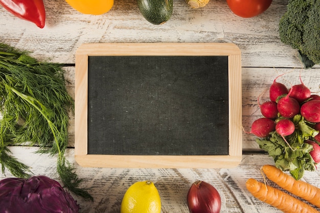 Free photo blank slate surrounded by various healthy food on wooden surface