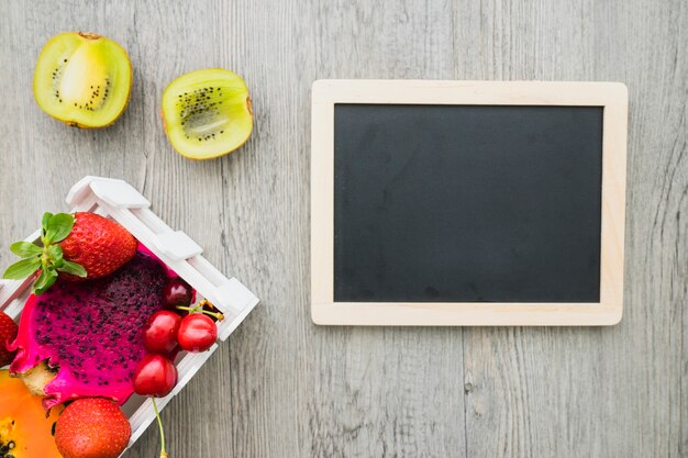 Blank slate and tasty fruits on wooden surface