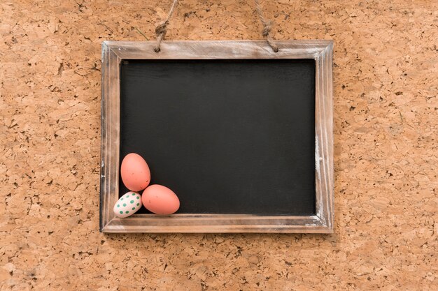 Пустой шифер с тремя цветными яйцами на Пасху день