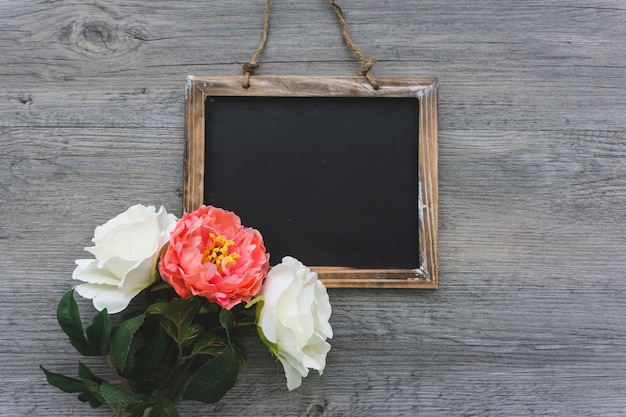 Free photo blank slate with three pretty flowers