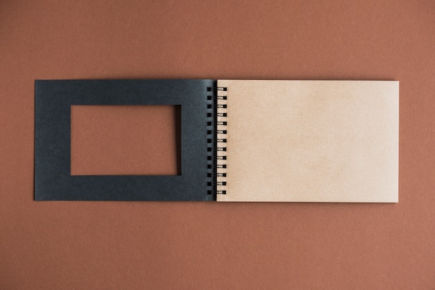 Blank spiral book with black cover on brown background