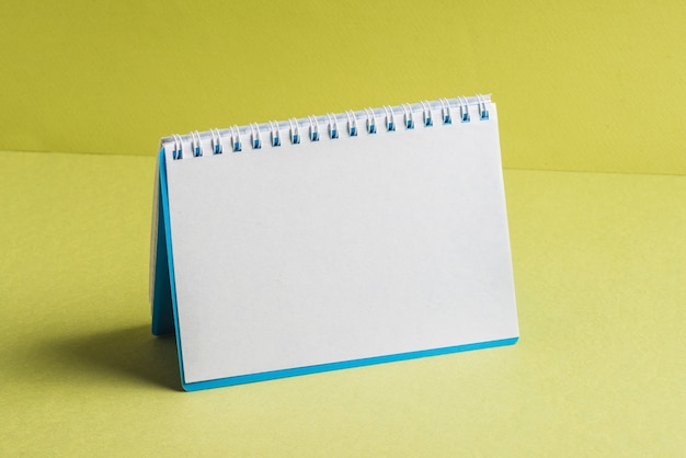 Free photo blank spiral book on yellow background