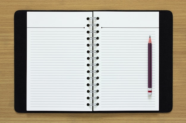 blank spiral notebook and pencil on wood background