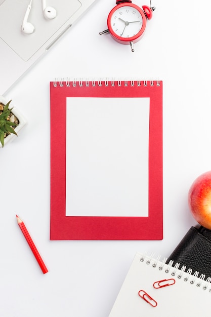 Blank spiral notepad,alarm clock,laptop,apple and spiral notepads on white backdrop