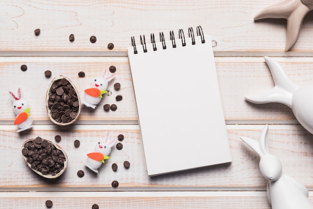 Blank spiral notepad; easter eggs with choco chips and bunnies on wooden backdrop