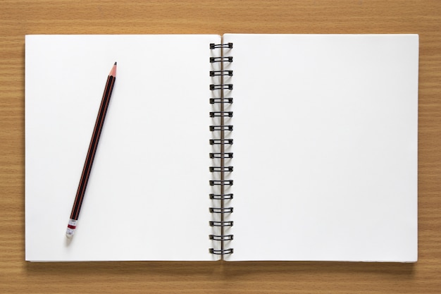 blank spiral notepad and pencil on wood background