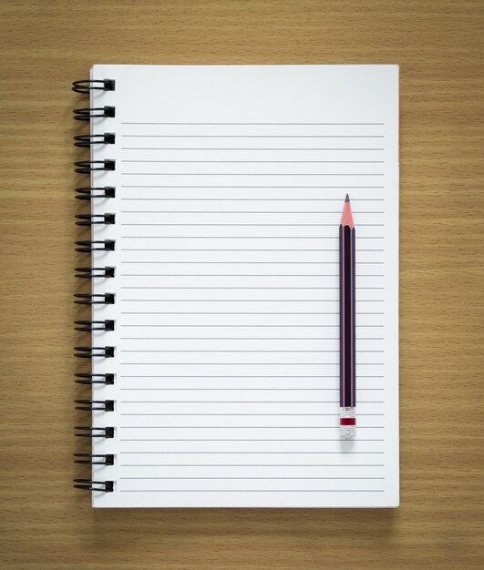 blank spiral notepad and pencil on wood background