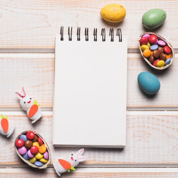 Blank spiral notepad with colorful gems; easter eggs; white bunnies on wooden desk