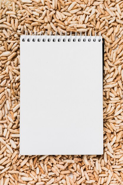 Бесплатное фото Пустой спиральный белый блокнот над коричневым пышным рисом