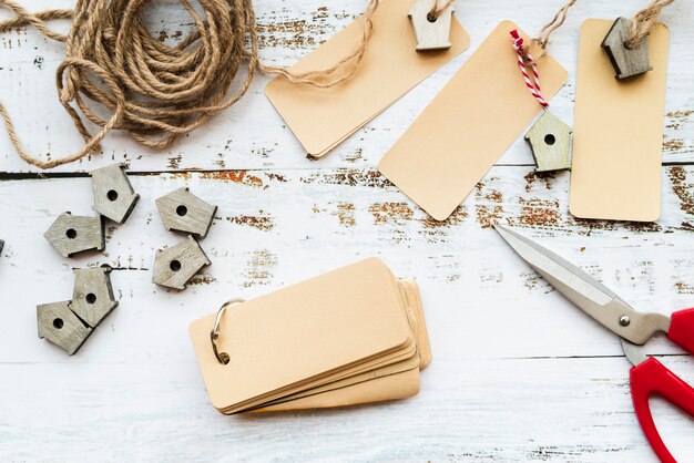 Blank tags; scissor; string and small birdhouses on white desk