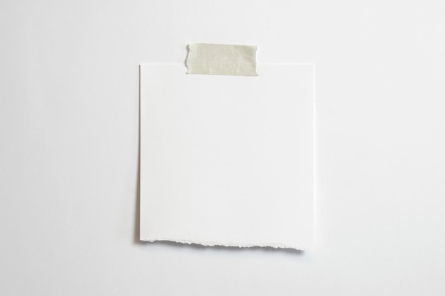 Blank torn photo frame with soft shadows and scotch tape isolated on white paper background 