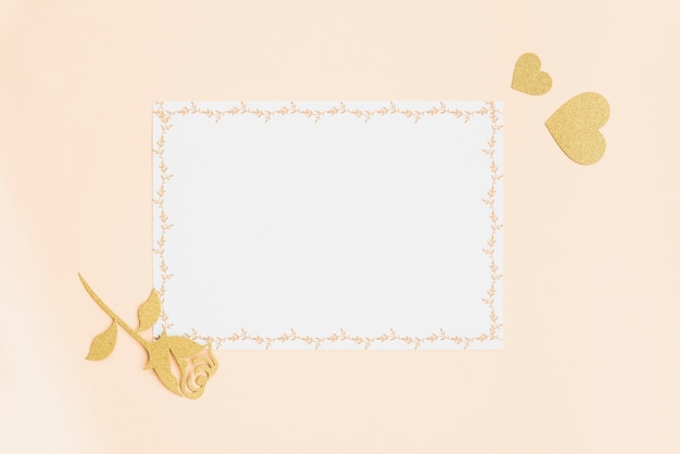 Пустая белая карточка с золотым сердцем и розы на цветном фоне