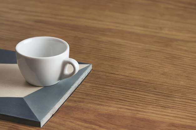 Blank white coffee cup on ceramic plate on thick wooden table in cafe shop.