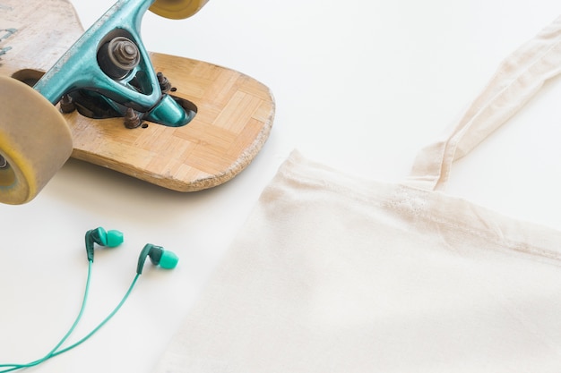 Blank white linen tote bag, skateboard and earphone on white background