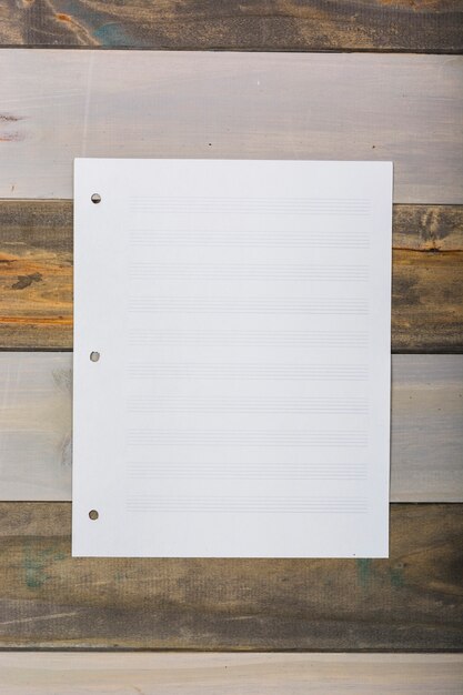 Blank white musical page stuck on wooden wall
