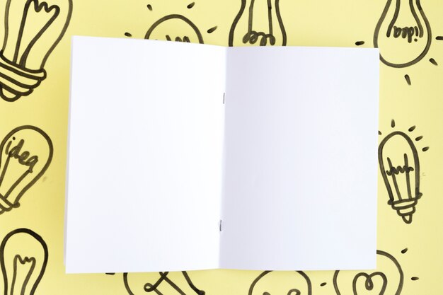 Blank white page on hand drawn light bulb over the yellow background