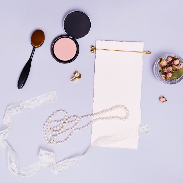 Blank white paper; dried pink rose bud in jar; ribbon; necklace; hairstick; oval brush; compact powder; golden hairpin and clutcher