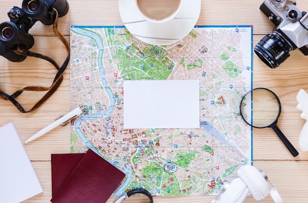 Blank white paper; tea cup and various traveler accessories on wooden background