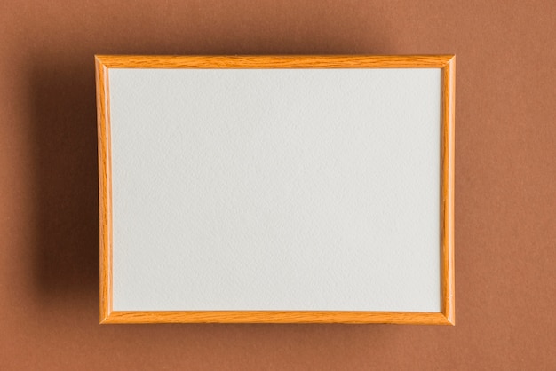 Blank wooden frame on colored wall