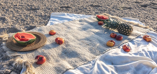 Blanket with fruits on sandy beach picnic concept