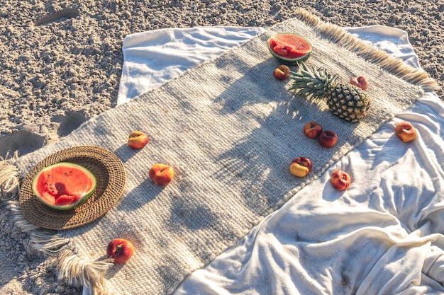 Blanket with fruits on sandy beach picnic concept