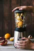 Free photo blender with various fruit on wooden background