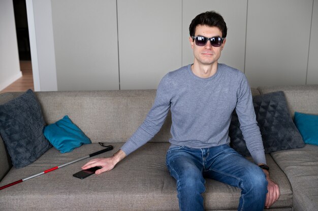 Blind man taking his smartphone from the couch