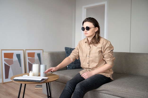 Blind woman taking a notebook while sitting on the couch