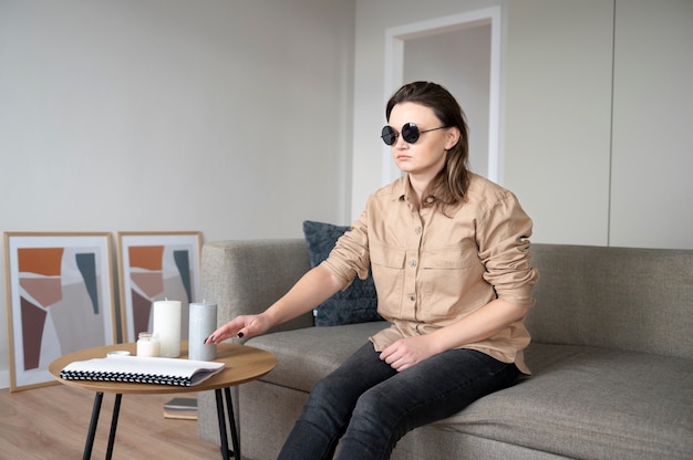 소파에 앉아 노트북을 복용하는 시각 장애인 여성