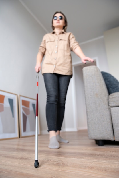 무료 사진 집 주변을 걷기 위해 지팡이를 사용하는 시각 장애인 여성