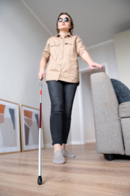 Blind woman using her walking stick to walk around the house