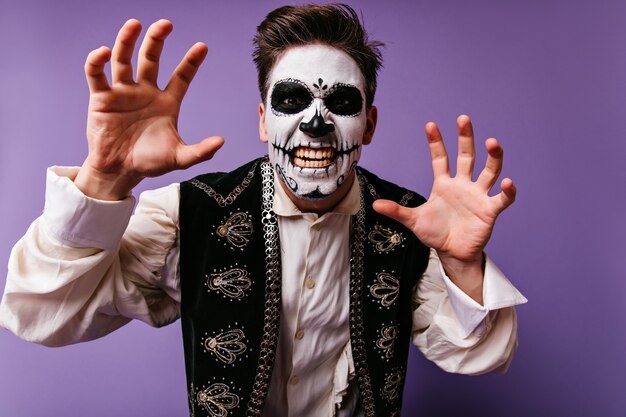 Блаженный кавказский парень развлекается в Хэллоуин. Забавный молодой человек с короткой стрижкой позирует в костюме зомби.